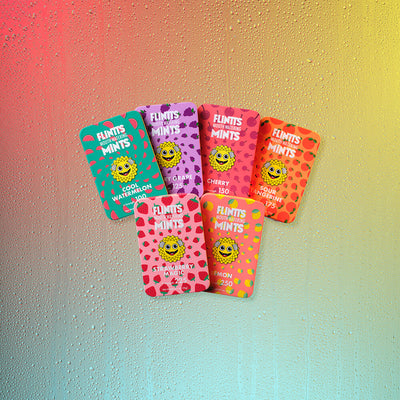 Six Flintts Mints tins in a rainbow arrangement featuring fruity flavors: Cool Watermelon, Strawberry Magic, Luxury Grape, Cherry, Lemon, and Sour Tangerine.